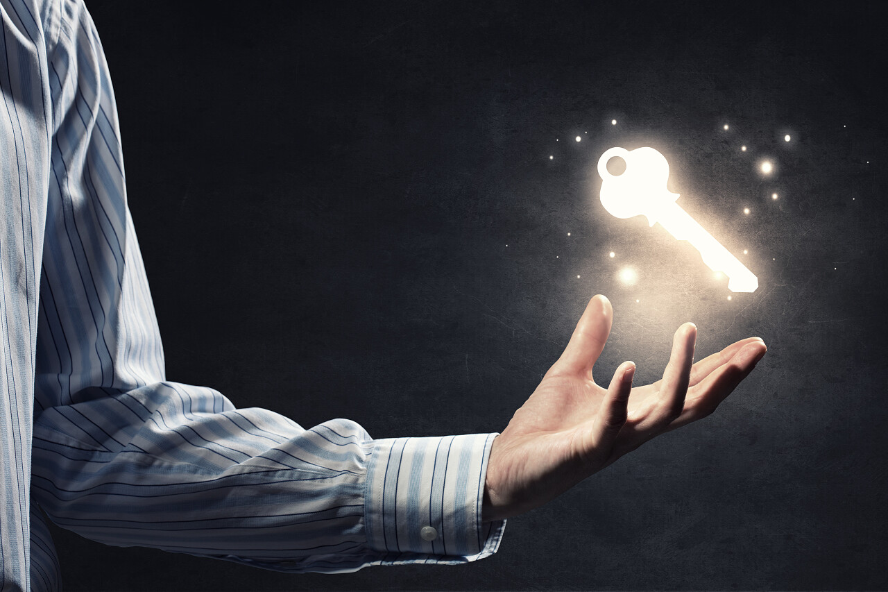 黑色背景上人类的手握著钥匙符号的特写