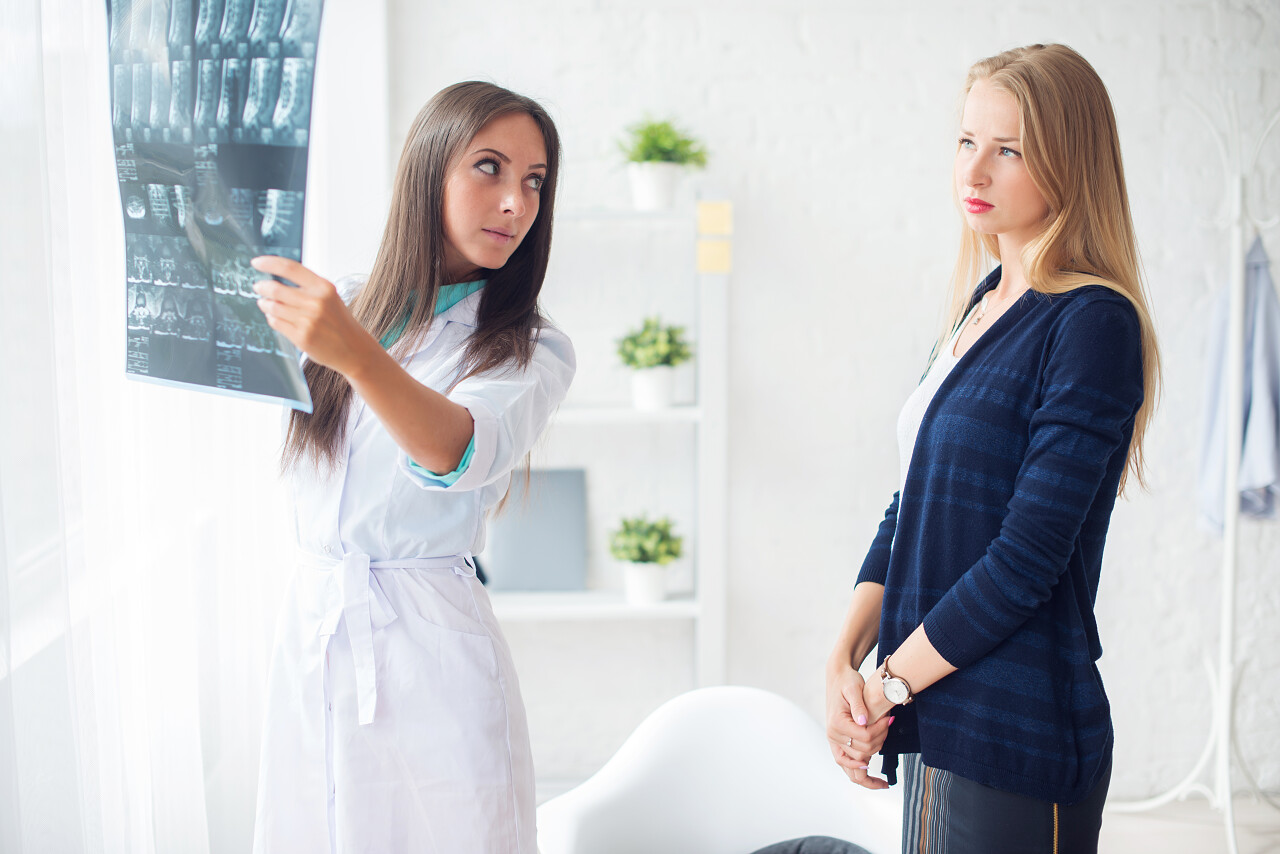 女医生在医院看着x射线胶片幷对女性病人交谈医生看诊病人