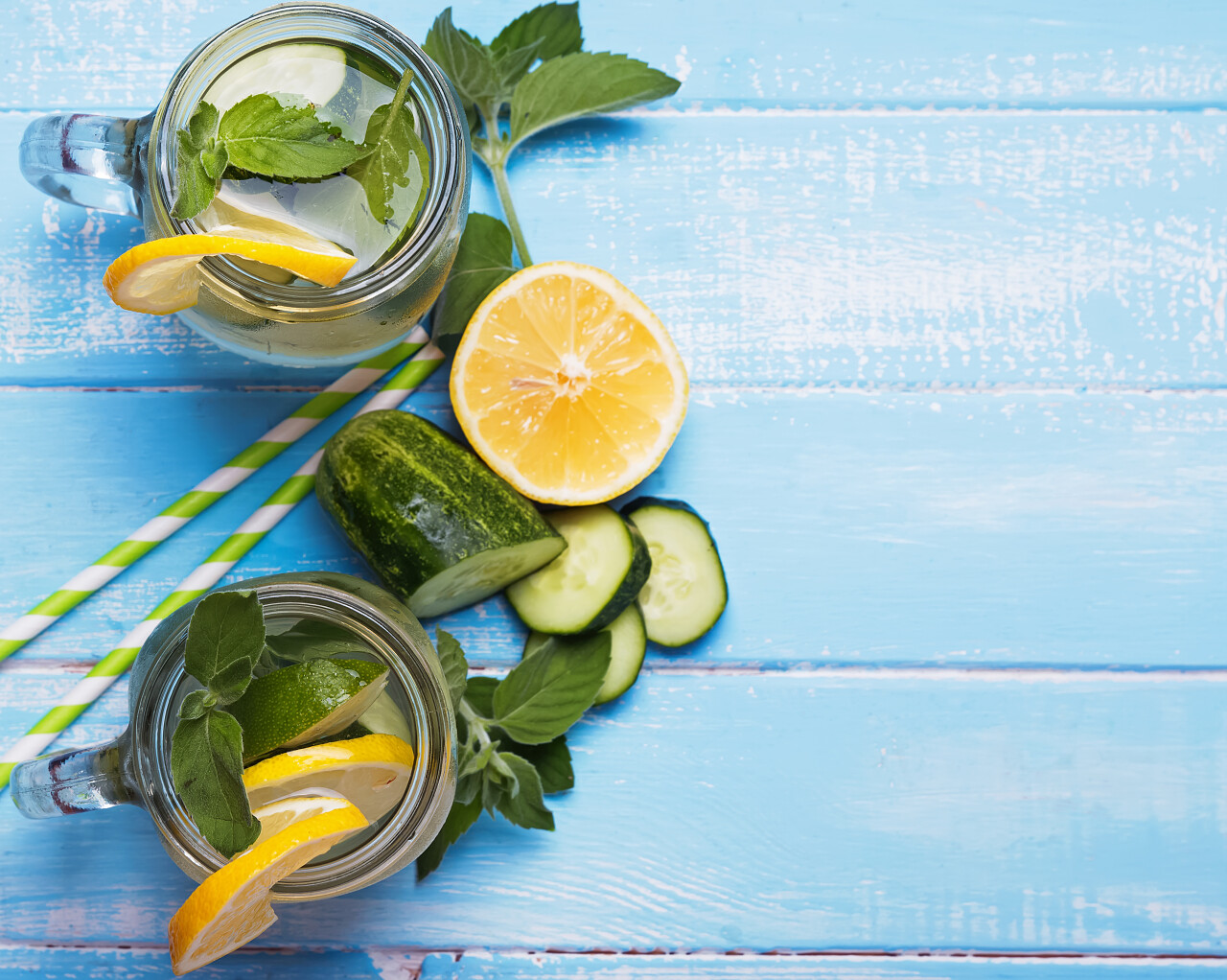蓝色木板上放着柠檬和黄瓜水