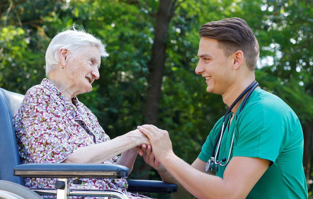 年轻的医生帮助残障的老妇微笑的老人