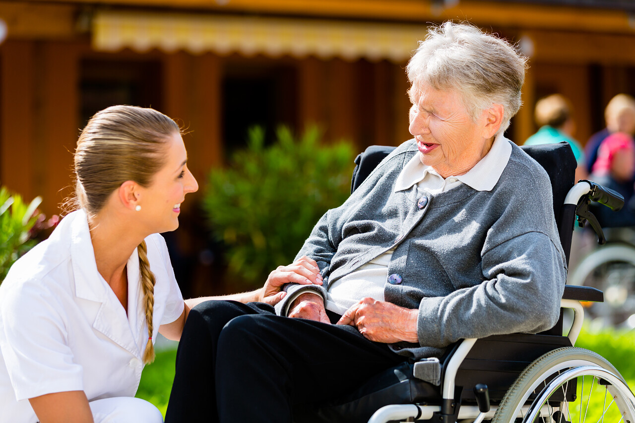 在夏天护士推老人步行穿过花园