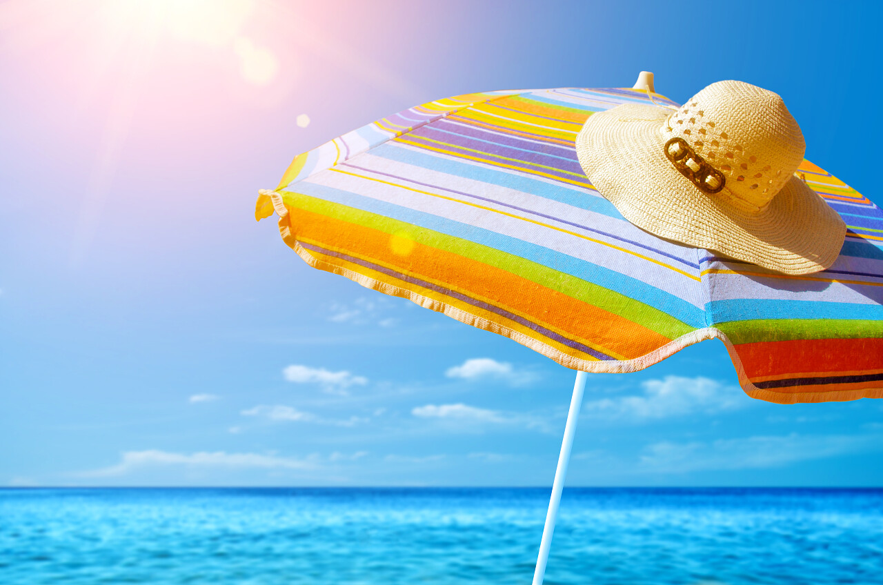五颜六色的遮阳伞和沙滩上阳光明媚的夏日草帽的细节