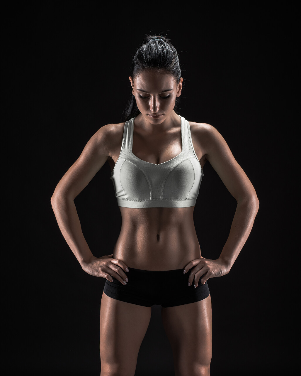 年轻的健身女人显示她完美的雕刻肌肉