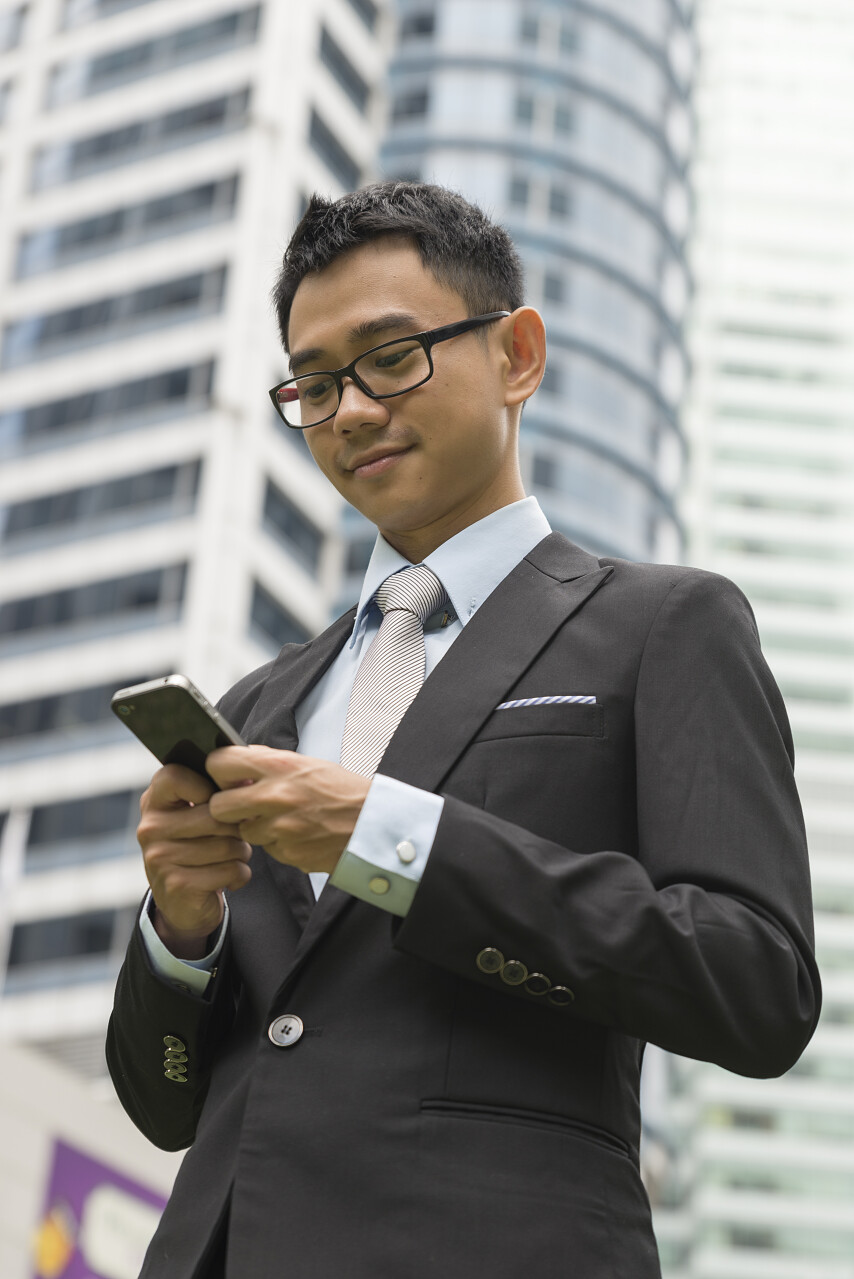 英俊的业务人通电话，写电子邮件或消息模型是亚洲男性