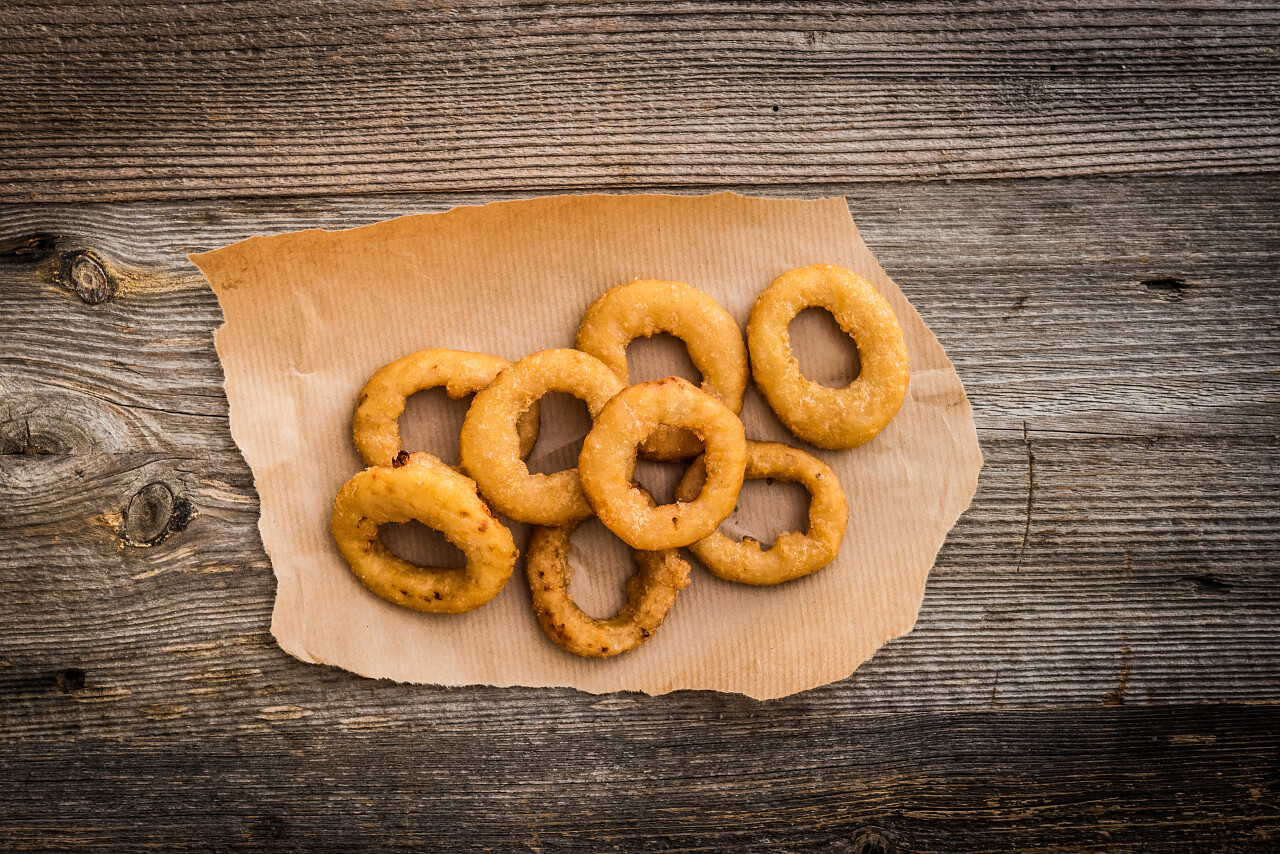 在木制的背景上的羊皮纸上的炸的洋葱圈