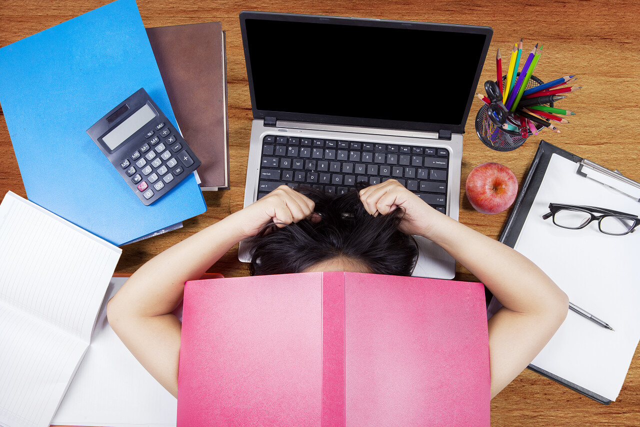 女性高中学生学习用手提电脑、书籍和文具在地上