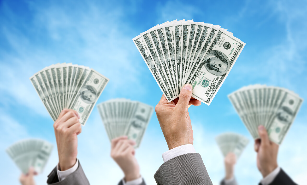 六只手举着纸币在天空背景下