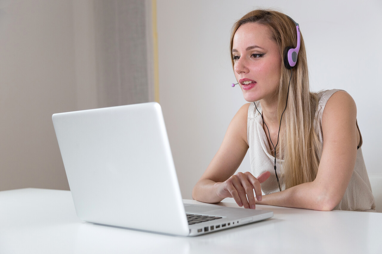 金发女郎与耳机笔记本电脑上工作