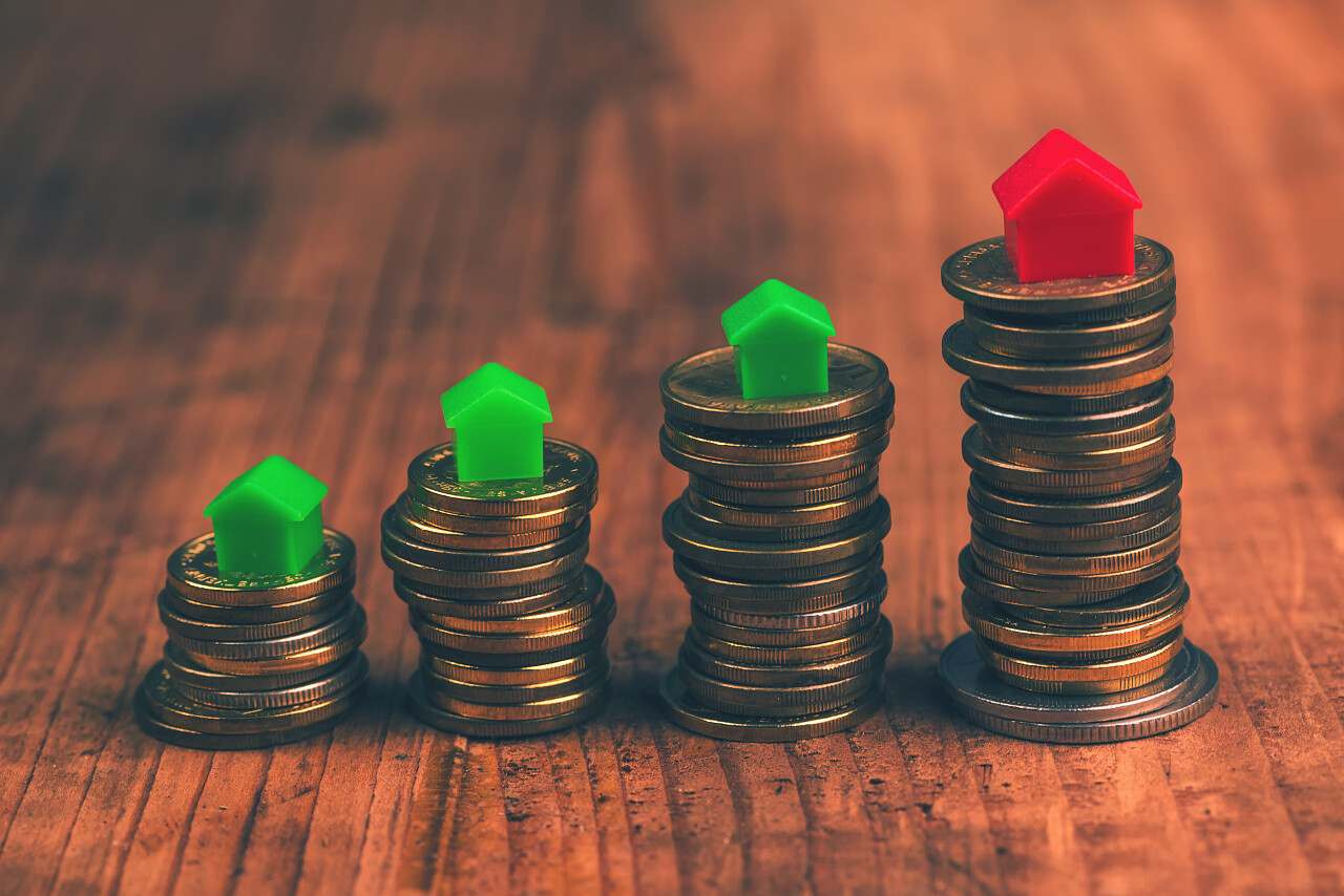 住房抵押贷款概念与小塑料房子模型上堆积的硬币.