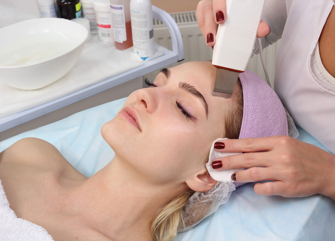 女人在美容厅接受专业的超声波设备清洗治疗