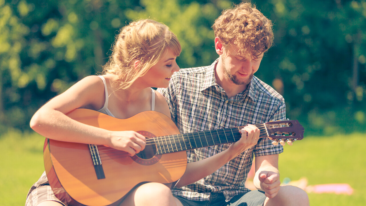 年轻的夫妇游客在露营时弹奏吉他