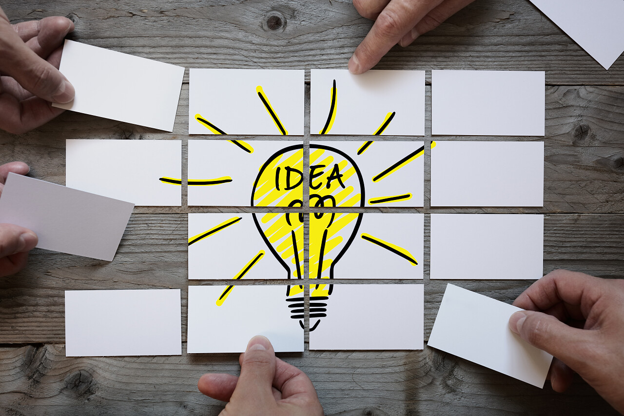 业务团队脑力激荡游戏用名片纸拼成灯泡思考