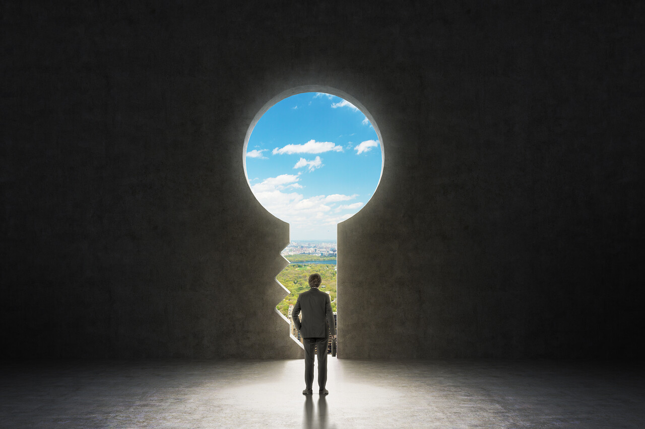 一个穿着正式西装的商人透过水泥墙上的钥匙孔看着纽约