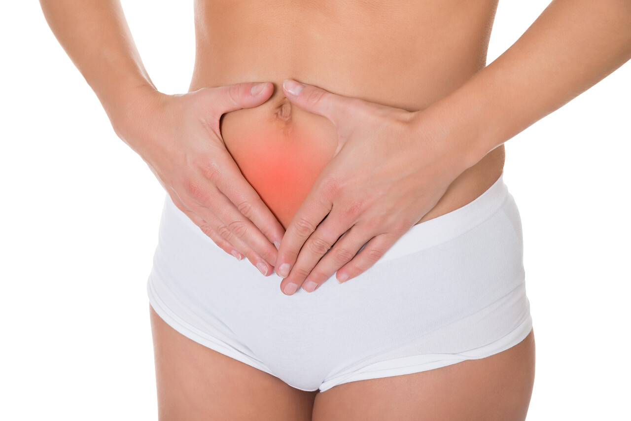 白色背景上年轻女子腹部的红色部分疼痛肚子痛