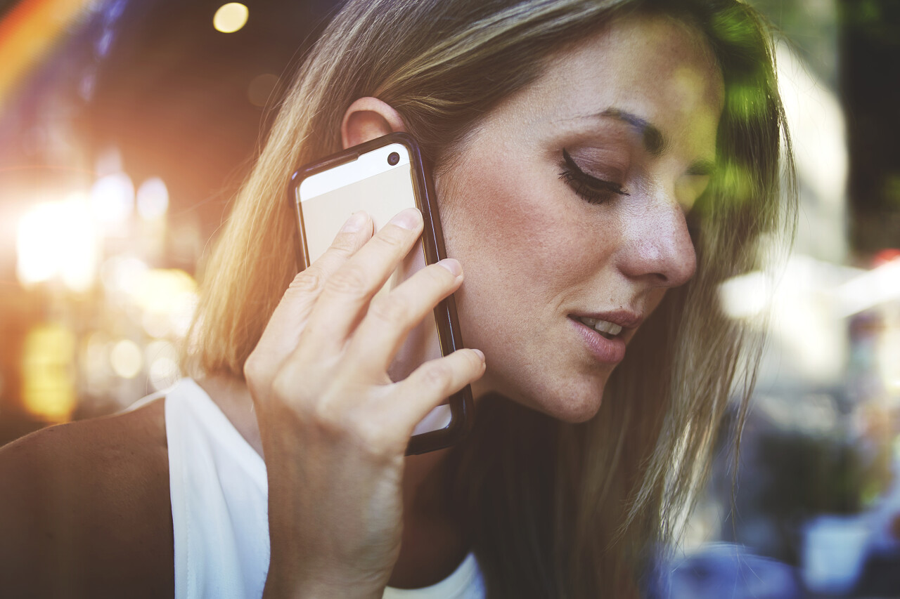 在城市灯光的照耀下美丽的女子正在用手机通话