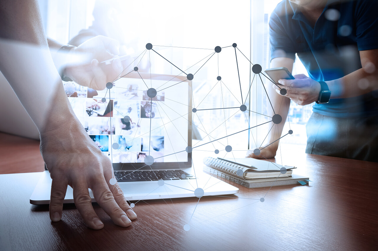 设计师在办公室的木制办公桌和两个同事讨论笔记本电脑上的数据