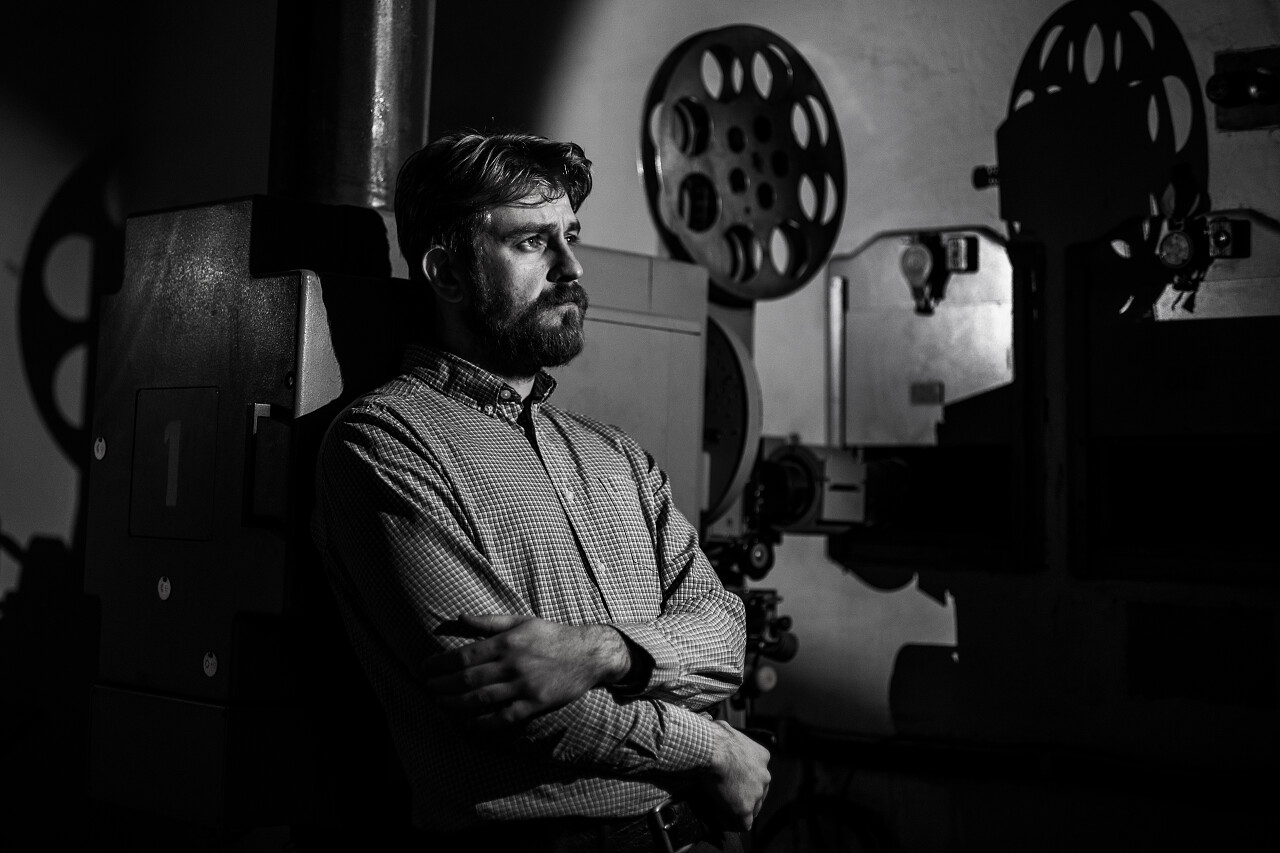 一位美丽又时髦的男人站在房间用老式放映机播放着电影