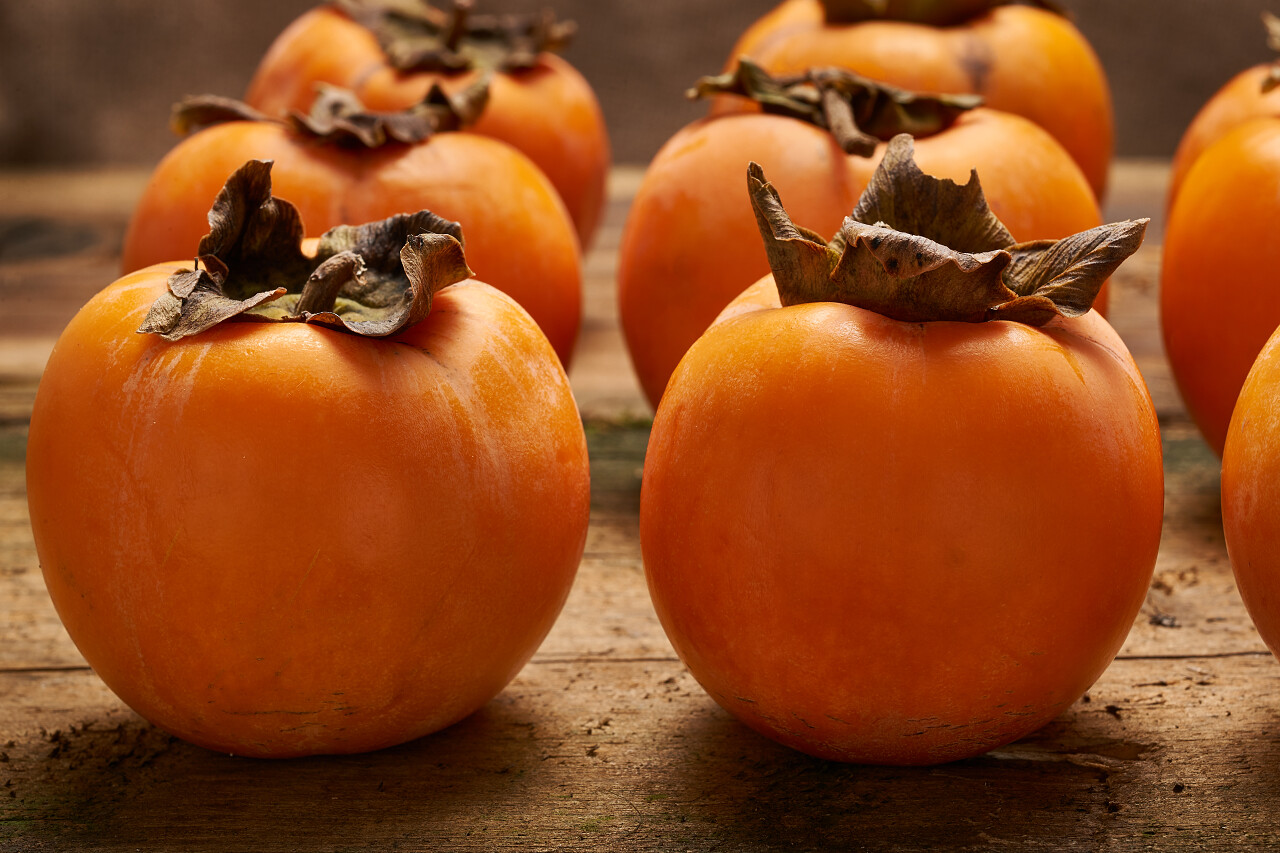 一个简约古朴的木质桌子上放了一堆黄色的柿子