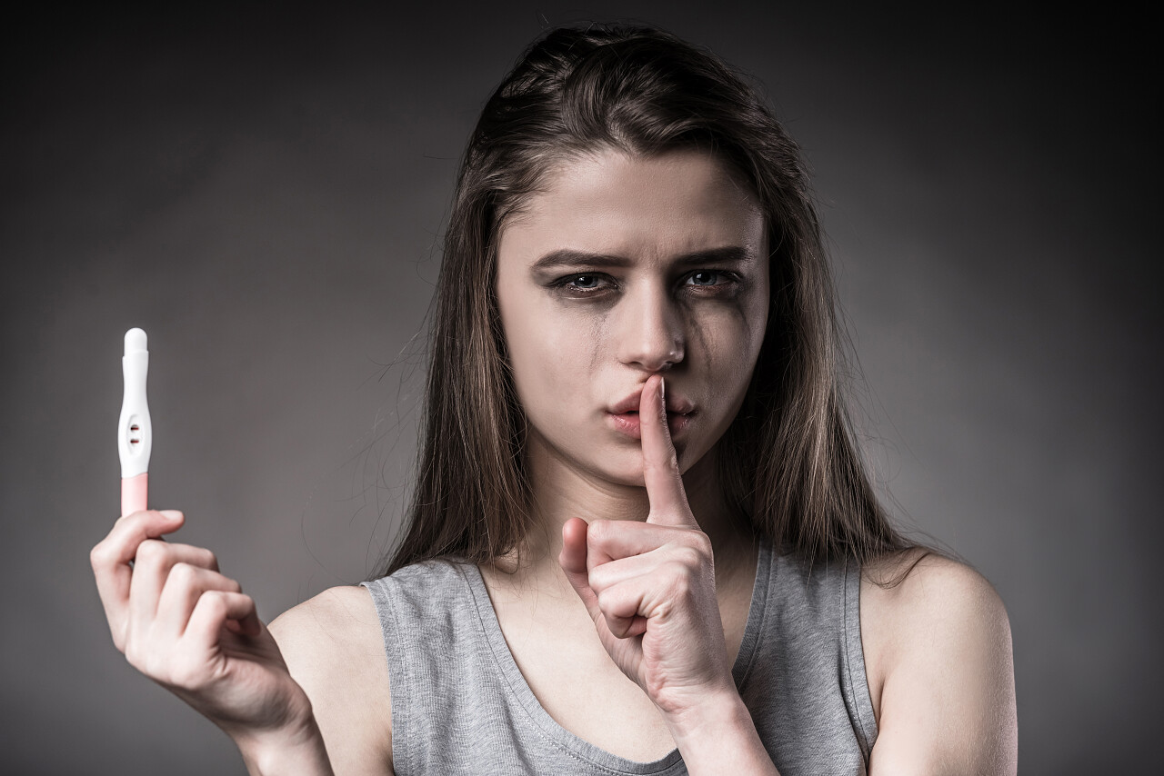 灰色背景下女人用嘘的手势拒绝堕胎烦躁恼火烦躁