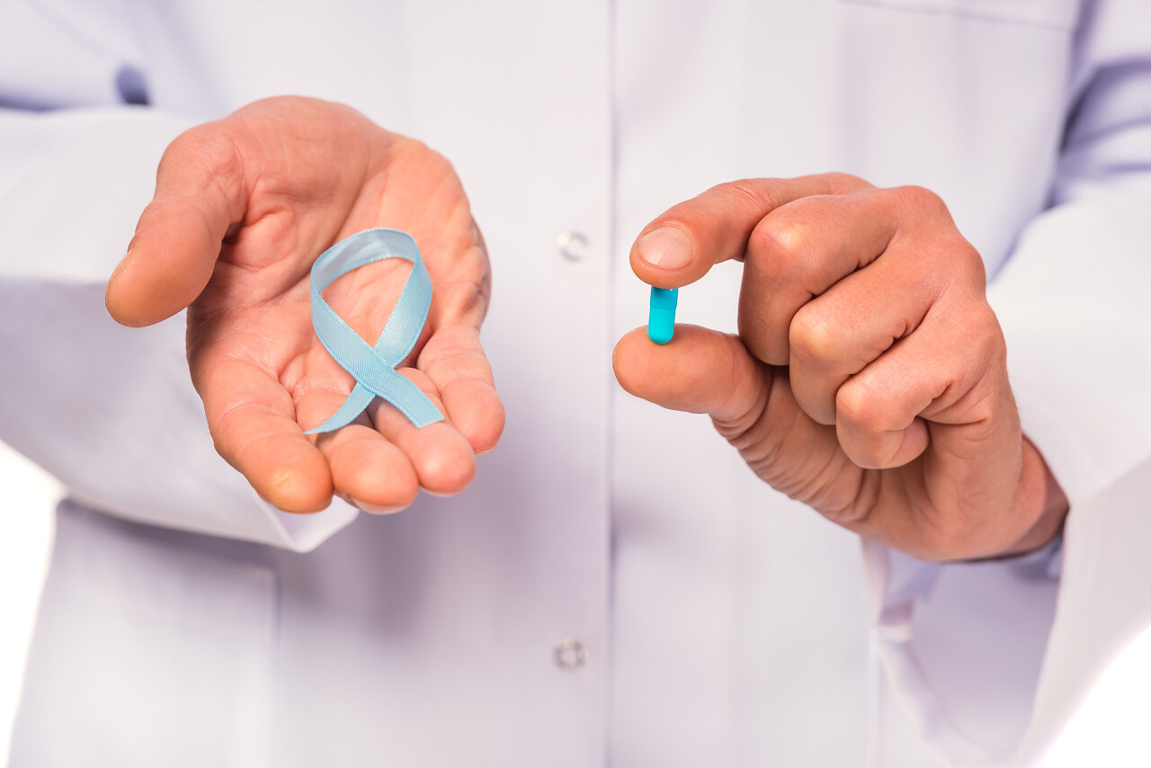 医生拿蓝丝带的手和拿着药丸的手的特写