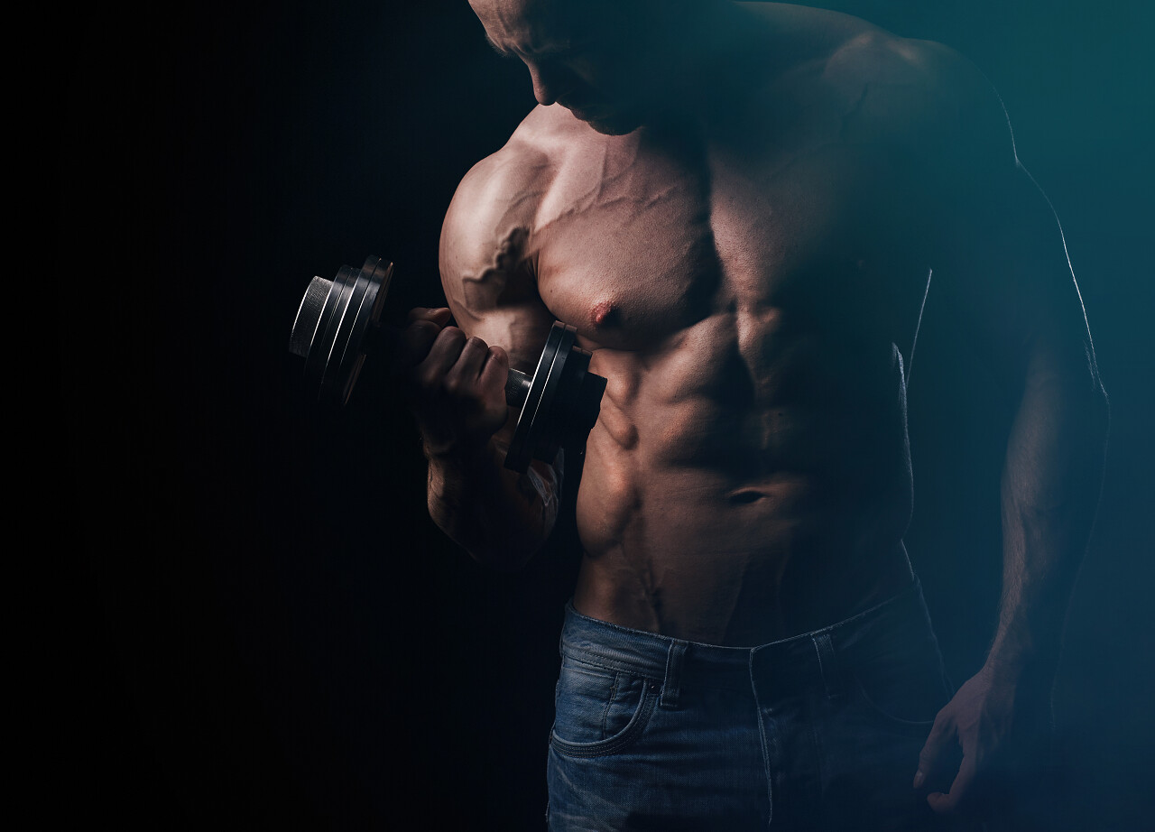 黑色背景下举着杠铃的肌肉男