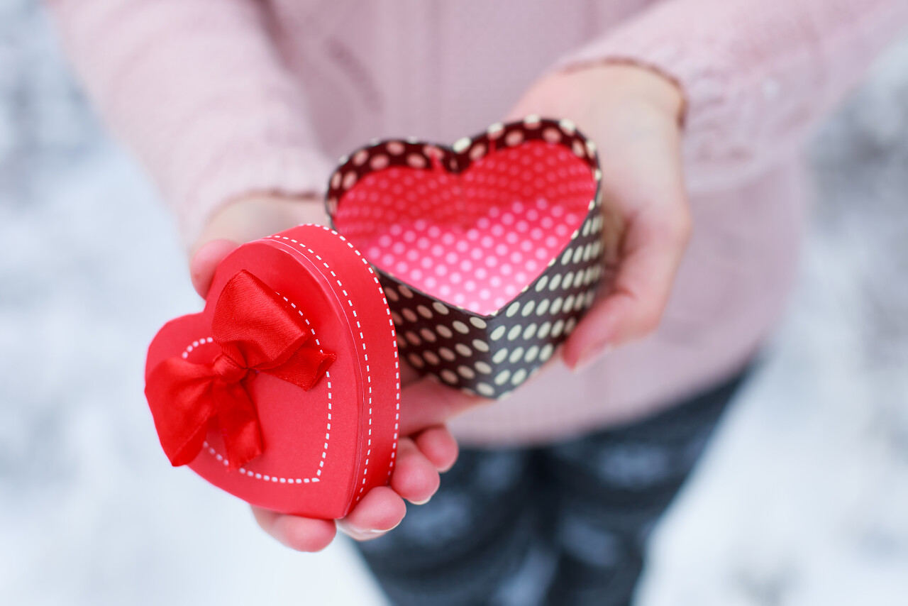 美女手拿着一个心形情人节和圣诞节主题的礼物盒日记情人节