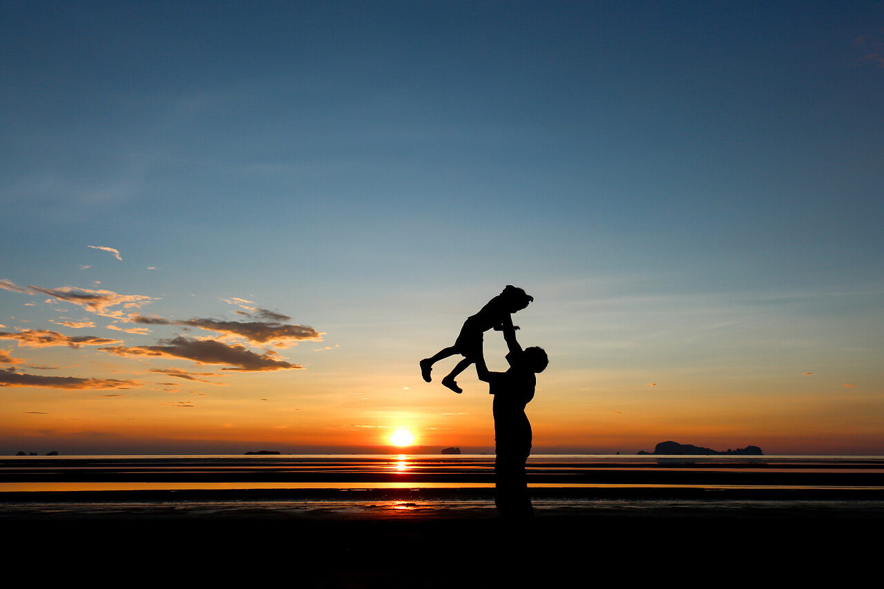 日落时一个男人和他的儿子一起在沙滩上玩耍的剪影幸福童年 孩子幸福的人美好童年