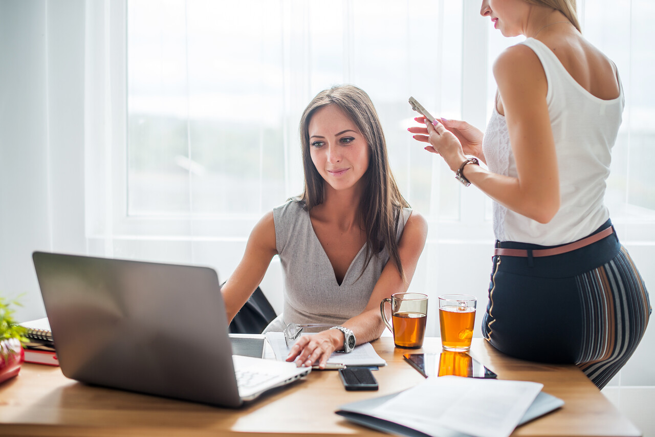 休息时间女子坐在办公桌前看着电脑聊天喝咖啡