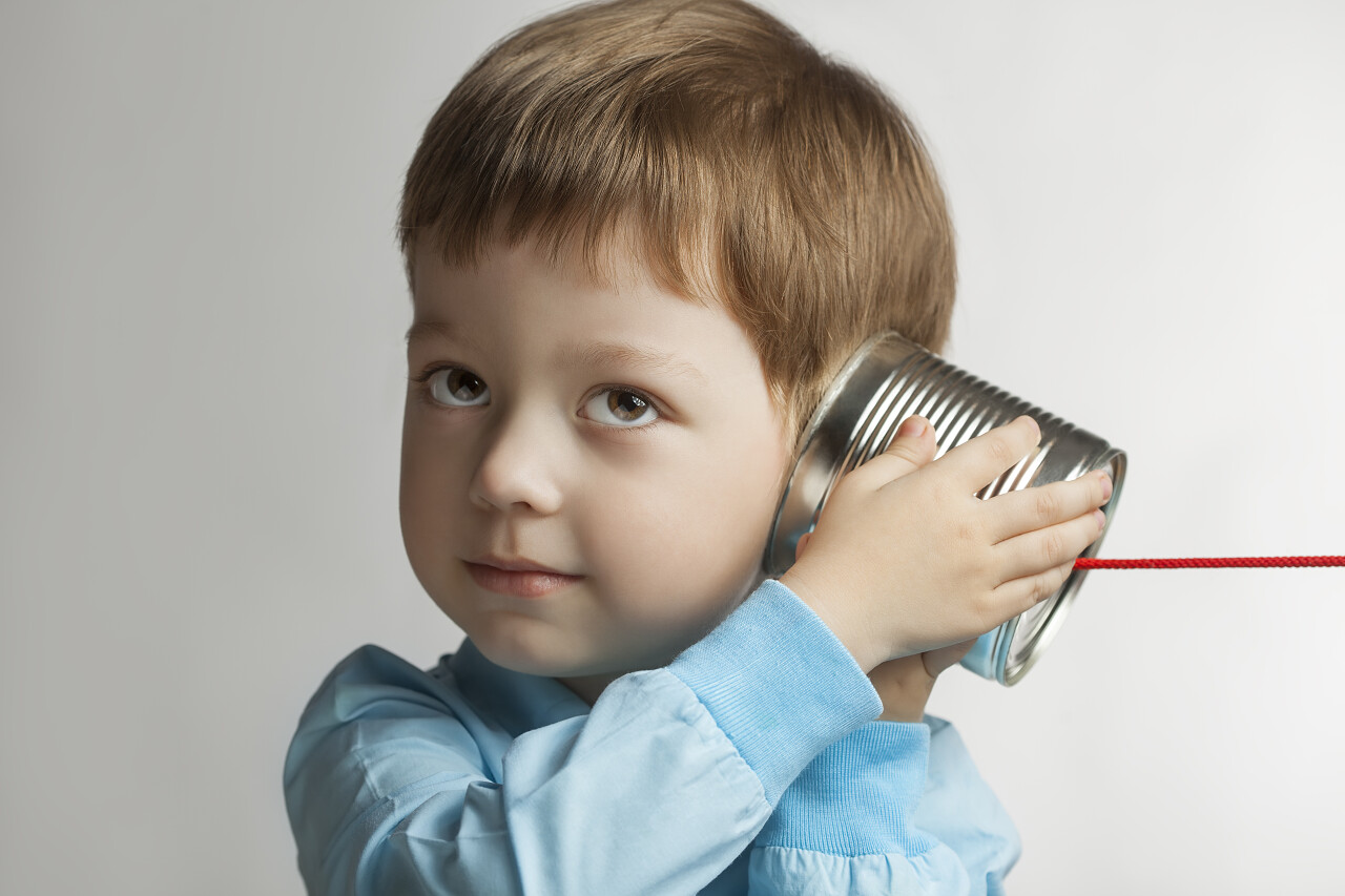 灰色背景下一个外国男孩子在听东西