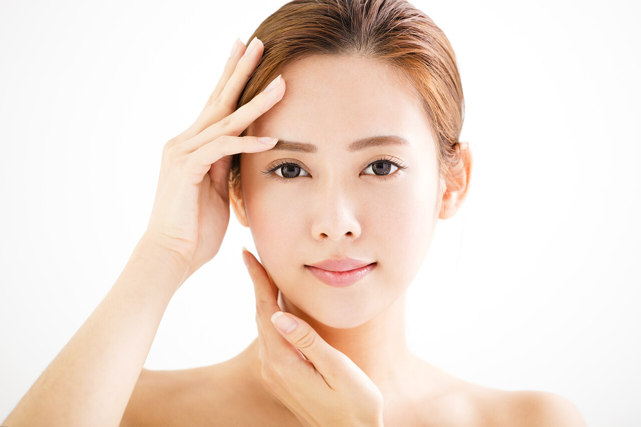 灰色背景下一个美丽的用手扶着脑袋的美女