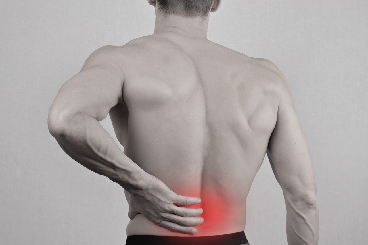 灰色背景下一个男生用手扶着病痛的背腰酸背痛
