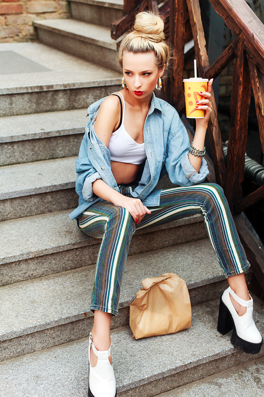 一个坐在楼梯上拿着饮品的时尚美女