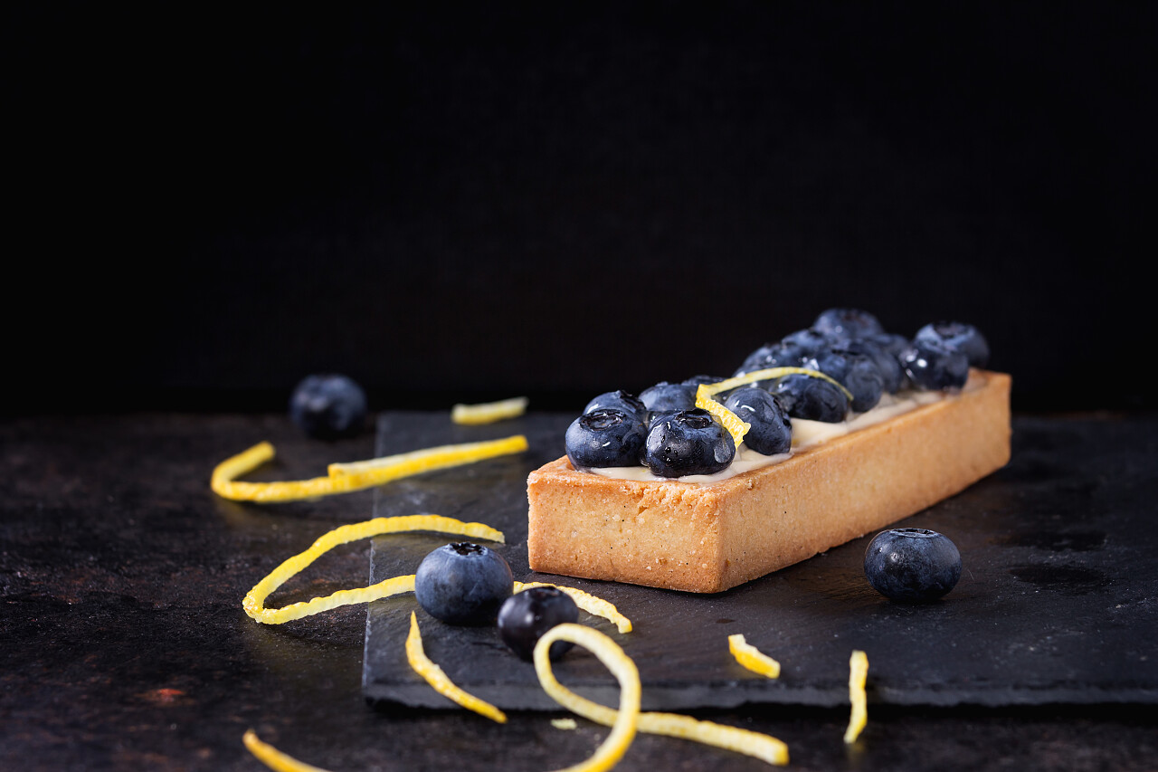 黑色背景上方形柠檬挞与蓝莓甜点