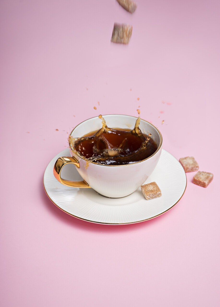 粉红色背景下弹夹的白色咖啡杯上一些红糖多维素