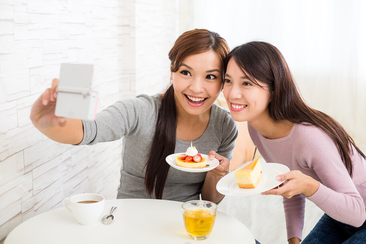 咖啡馆里拍照片的亚洲年轻女性