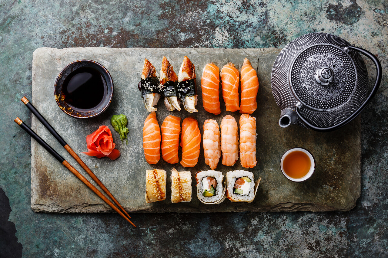 灰色石材板上金属背景的寿司套餐与茶