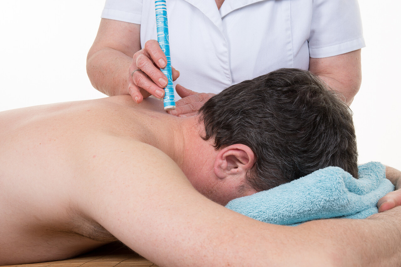 白色背景下女性治疗师在一个男人的背影上在中医工作