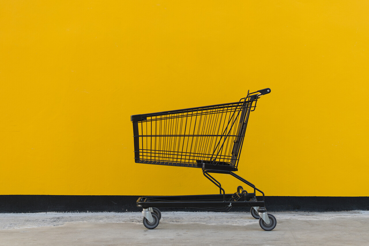 黄色背景下一辆极简主义风格的黑色购物车