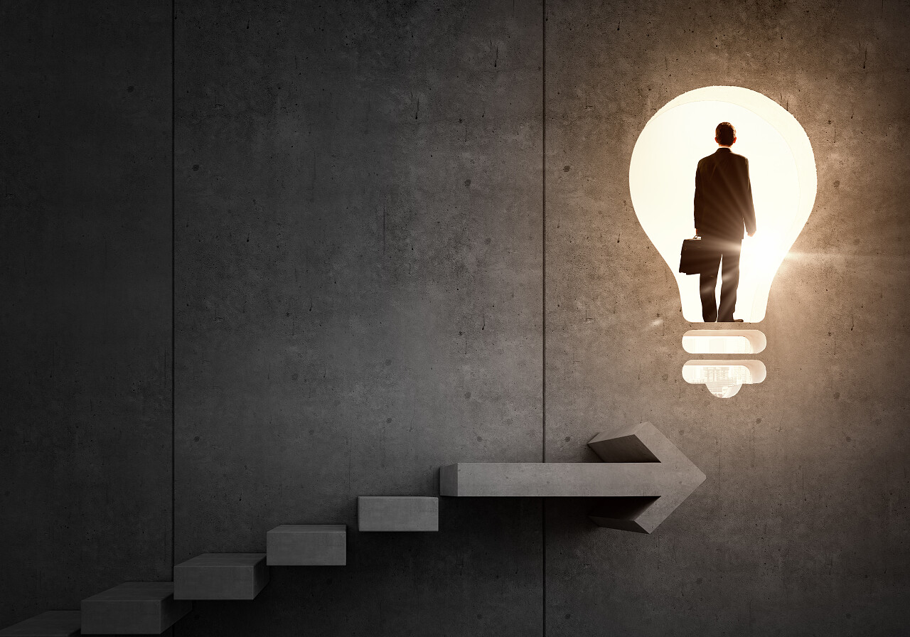 灰色背景下商人站在梯子上的创意灯泡里思考