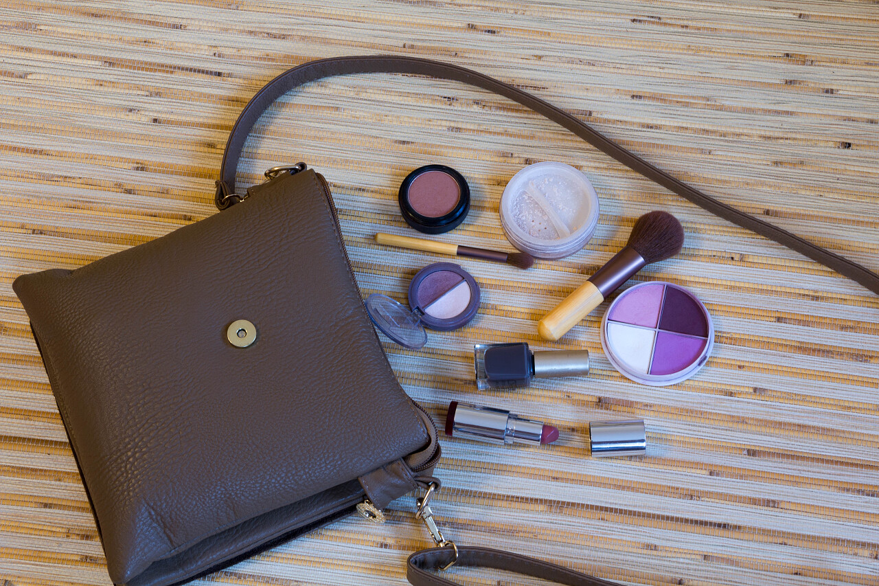 灰色背景上放着女士包包和化妆品阴影