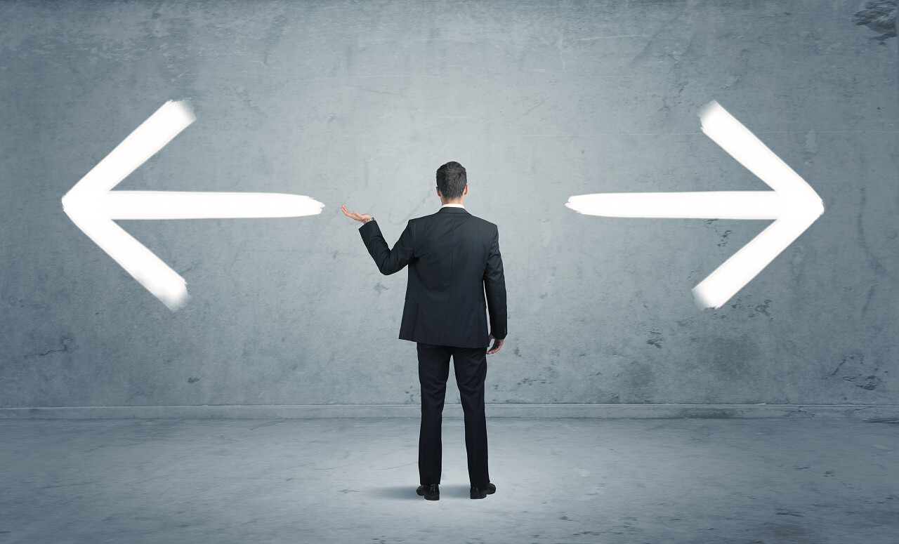 商人对着灰色背景上两种不同方向的箭头选择困难症