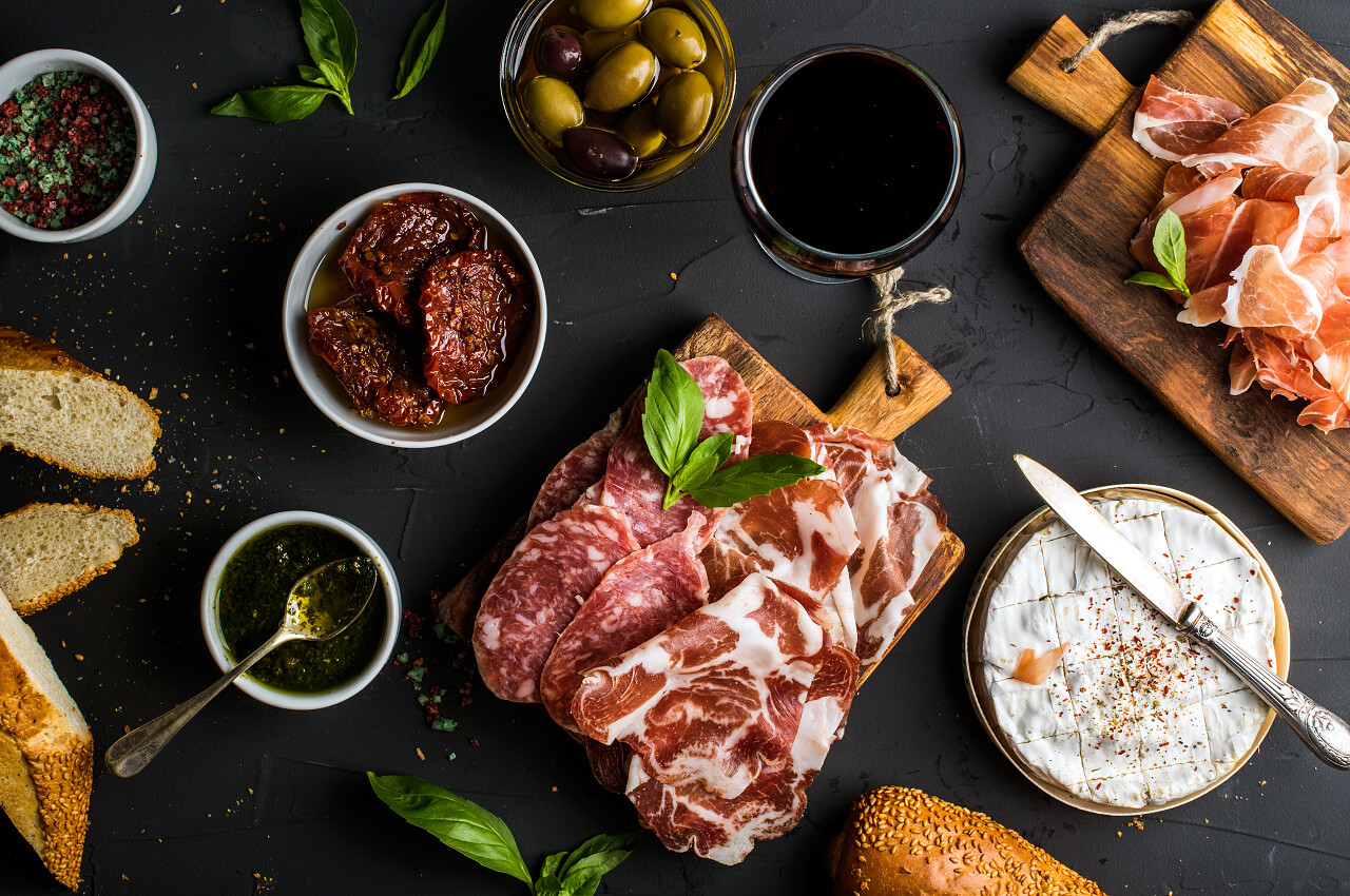 黑色背景上橄榄番茄干法式面包奶酪和香料旅游美食