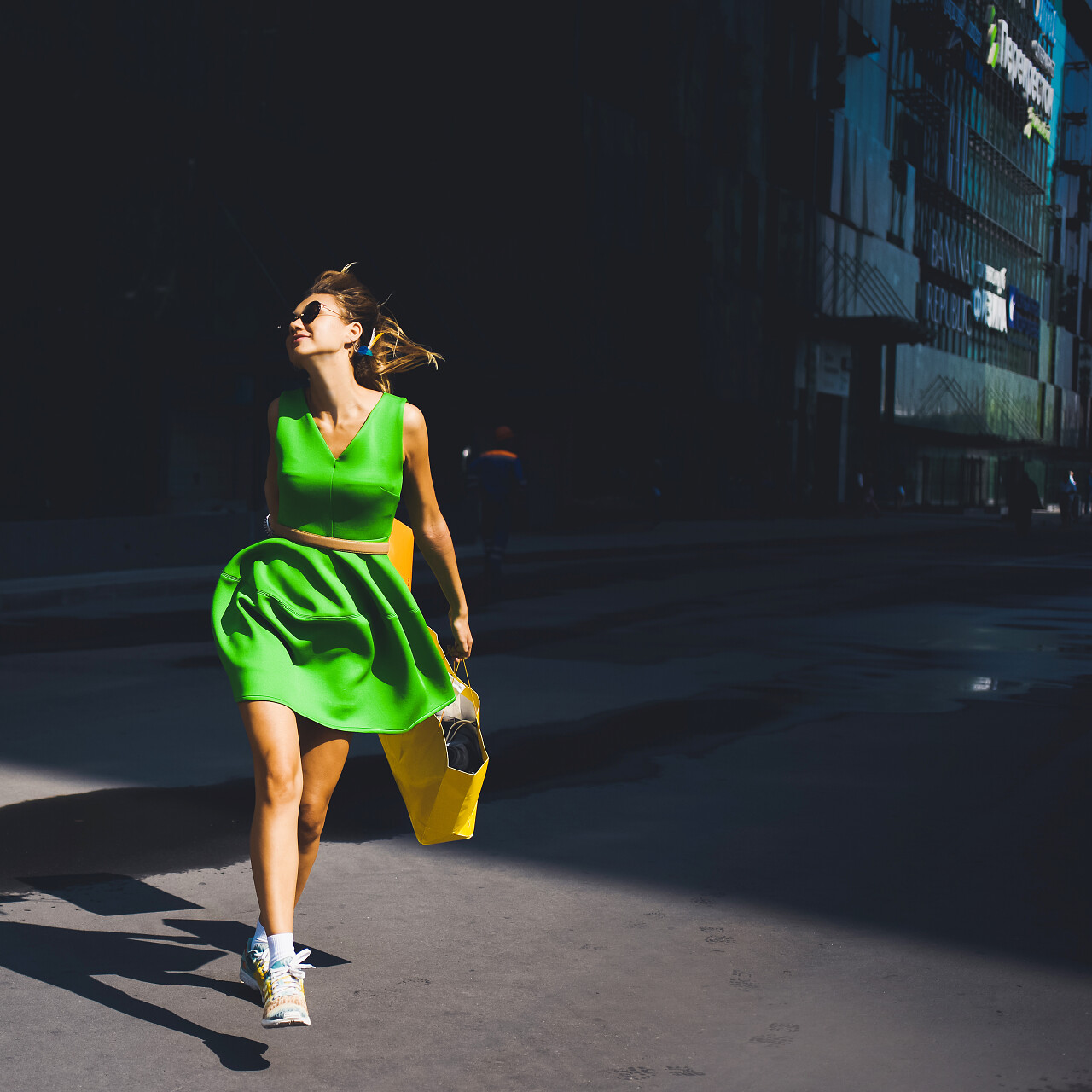 阳光灿烂的日子年轻漂亮的女孩在城市街道上购物