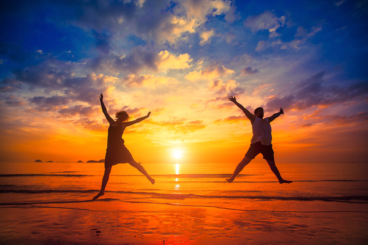 年轻人在日落时的海滩上跳舞剪影