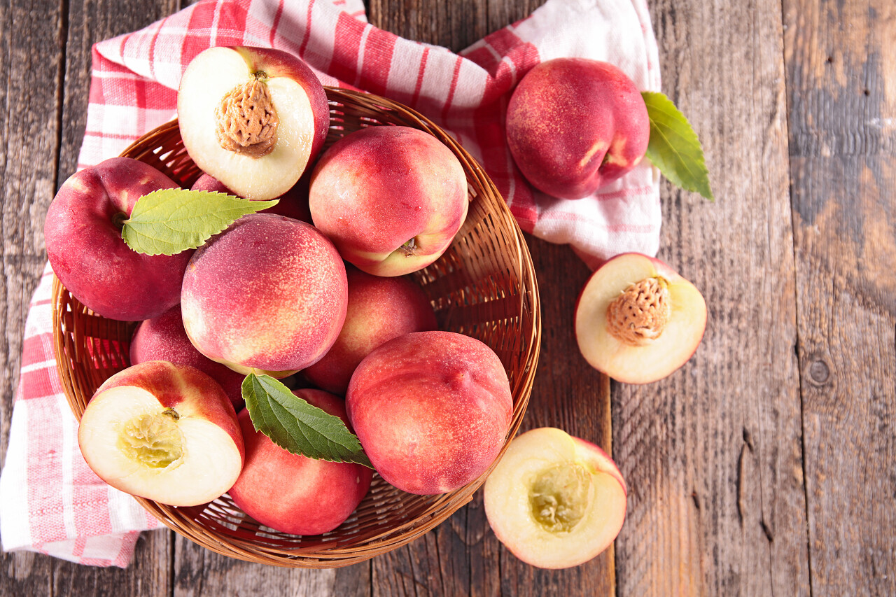 在桌上的篮子里的新鲜生桃子