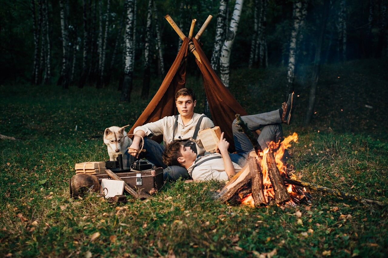 赫斯基狗和坐在篝火旁的两个孪生兄弟