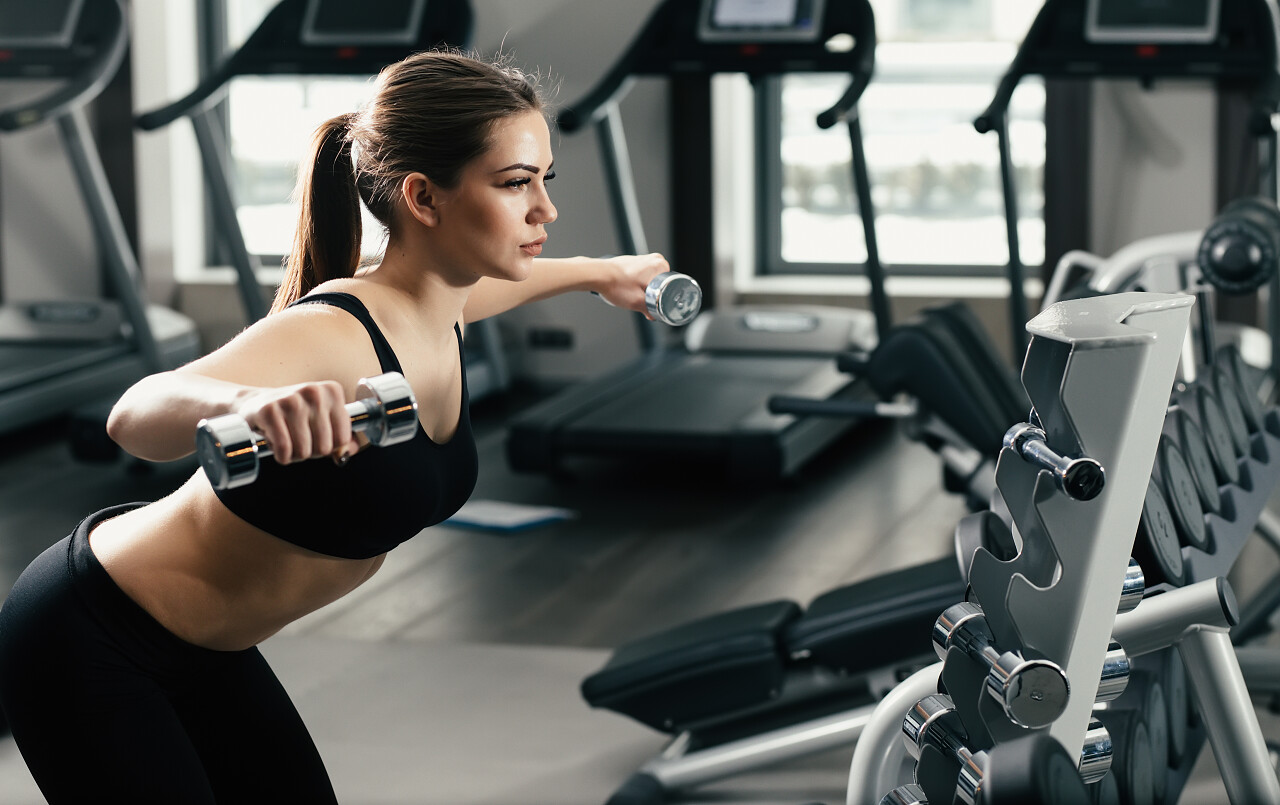 与哑铃在健身房锻炼的年轻女人
