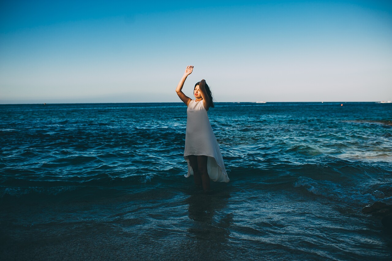 在希腊海滩上穿白裙子的年轻性感的美女