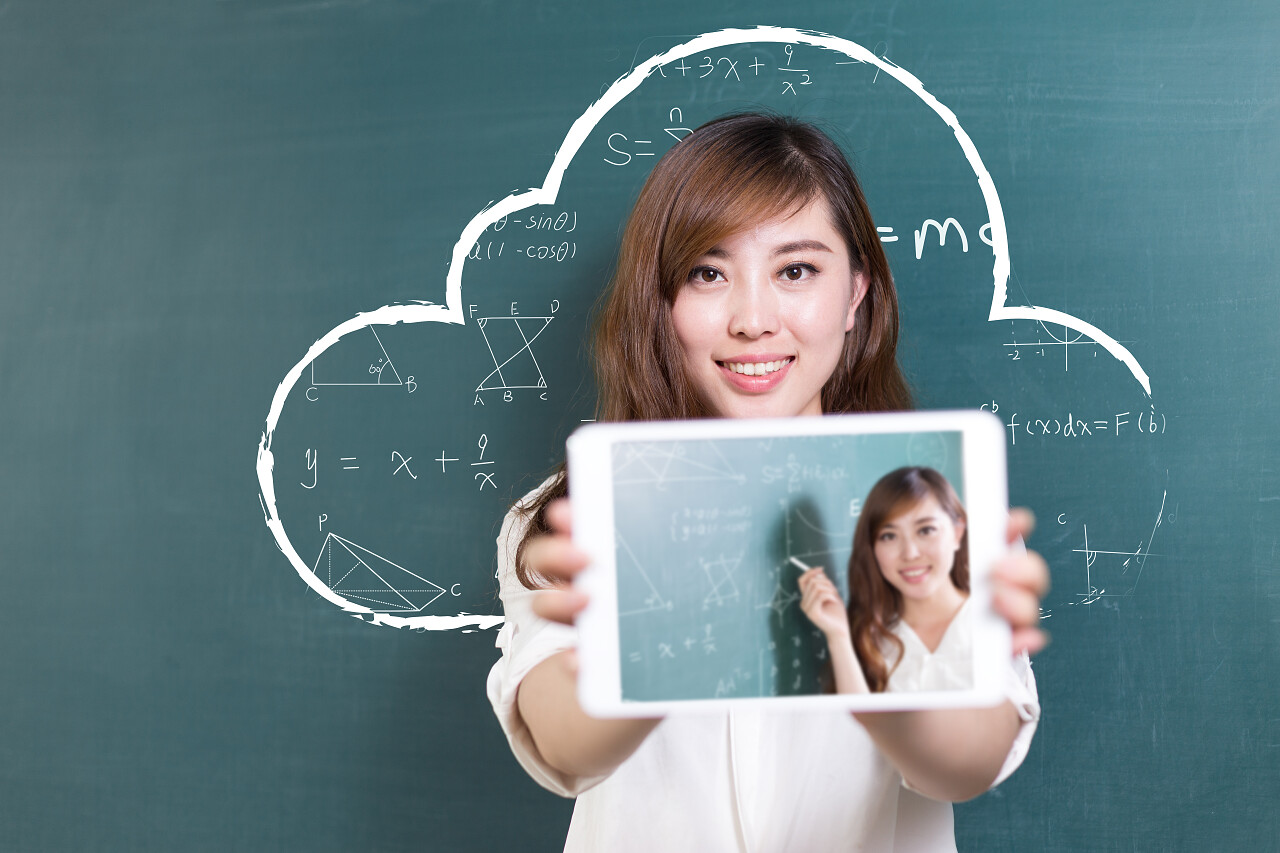 老师拿着平板站在绿色黑板前