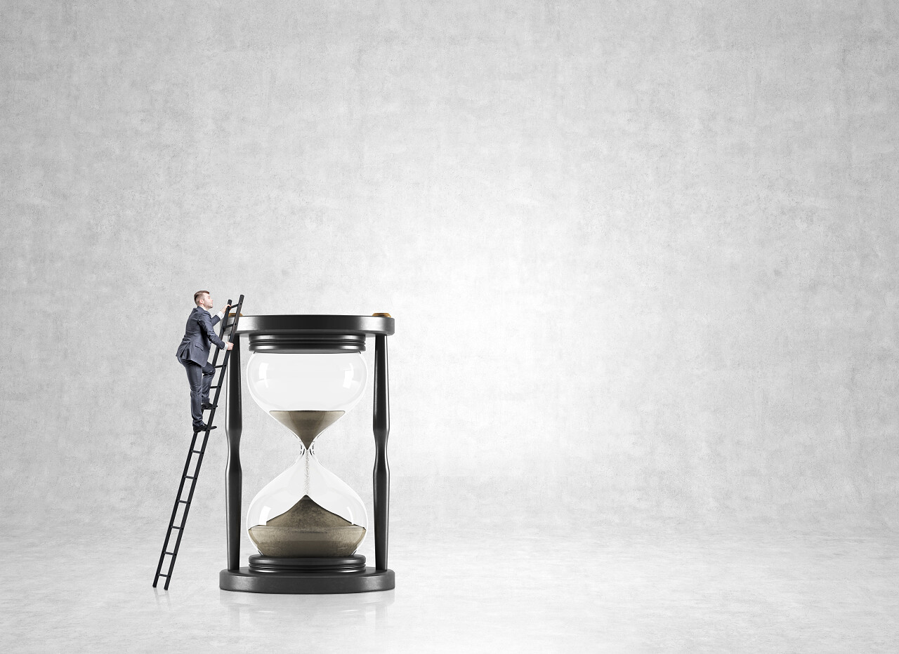 在白色的背景上放着一个巨大的沙漏旁边的男性商务人士正在爬梯子